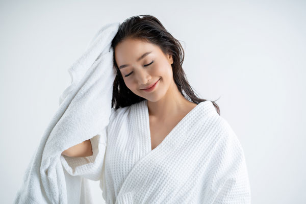 A woman scrubbing her hair using a white towel