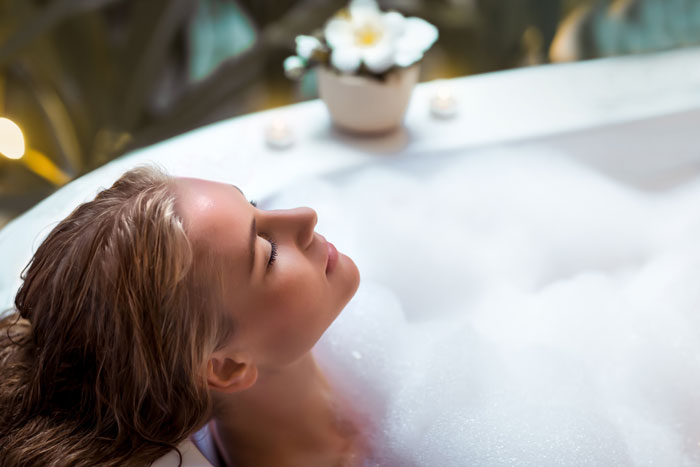 A woman relaxing on a bathtub full with foam