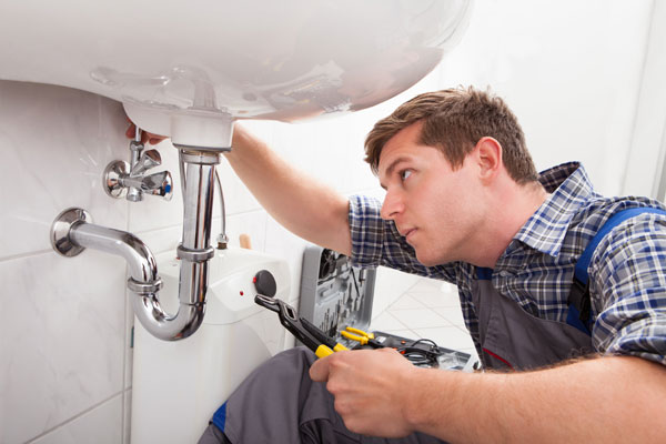 A technician is intalling a water heater shower in the bathroom