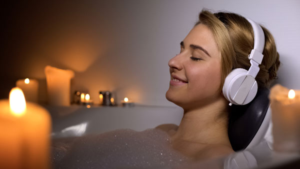 A young lady having a relaxing bath while wearing a headphone